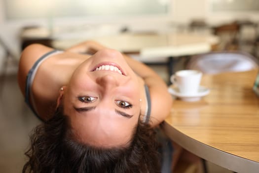 Funny portrait of a happy woman joking in a bar looking at you