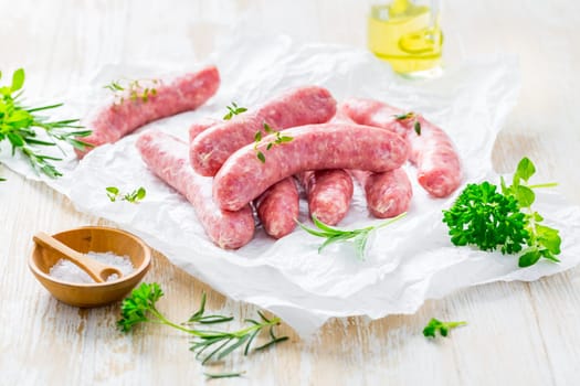 Raw sausages prepared for BBQ and grill with herbs and onions