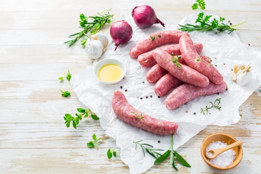 Raw sausages prepared for BBQ and grill with herbs and onions