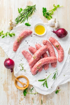 Raw sausages prepared for BBQ and grill with herbs and onions