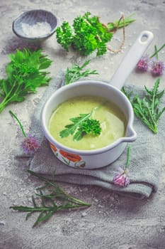 Healthy homemade green herb soup in pot made from local wild and garden herbs on grey