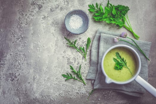 Healthy homemade green herb soup in pot made from local wild and garden herbs on grey