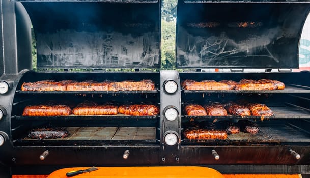 Large barbecue smoker grill with grilled meat wrapped with bacon. Street food.