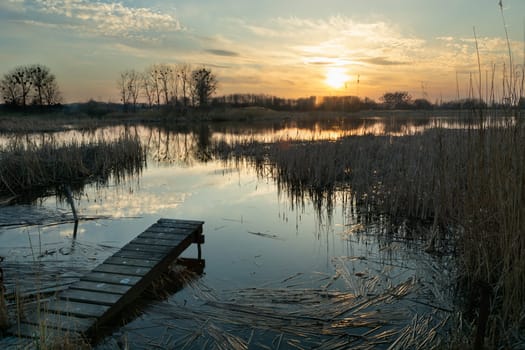 A small footbridge on the shore of a lake and sunset, Stankow, Poland