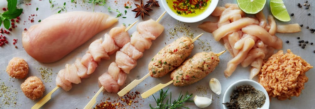 Top view of uncooked lula kebab and chicken skewers served on gray background with mix of raw meat and condiments