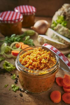 From above jar with tasty vegetable conservation placed on table with chopped raw ingredients in light kitchen during cooking preparation
