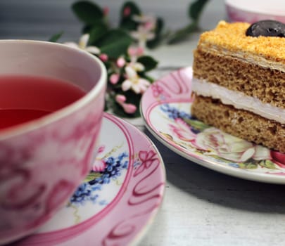 A cup of tea and a close-up cake on a wooden table..