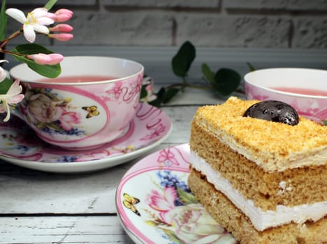 Two cups of tea and a close-up cake on a wooden table..