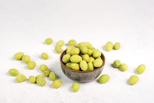 Pile of green wasabi coated peanuts in a bowl, spicy snack, oriental food