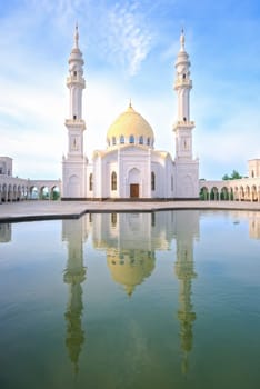 White Mosque, Bolgar, Tatarstan. A beautiful white mosque with domes and minarets against a bright blue sky. In the foreground is a reflection in the water.