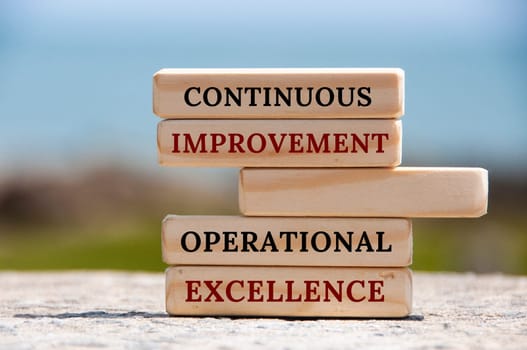 Continuous improvement Operational excellence text on wooden blocks with blurred nature background. Business concept