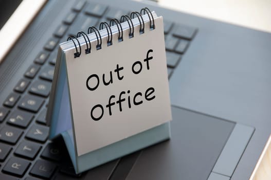 Out of office text on calendar desk on top of a laptop. Business concept