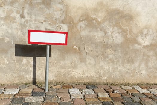 empty white sign with text space at the roadside in front of a house wall