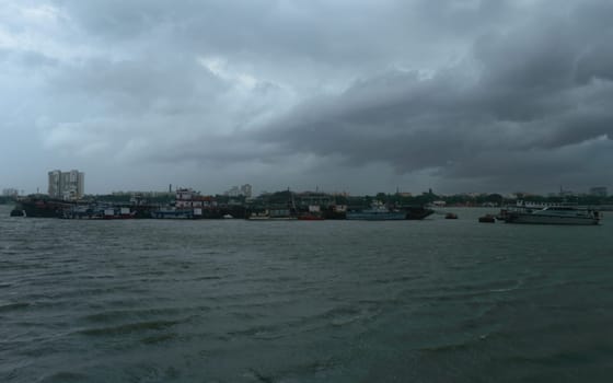 Ferry Boats floating over Ganges River at a distance on a Dramatic cloudy day. Beautiful Landscape View horizon from Babu Ghat. Kolkata West Bengal India South Asia 19 June 2022