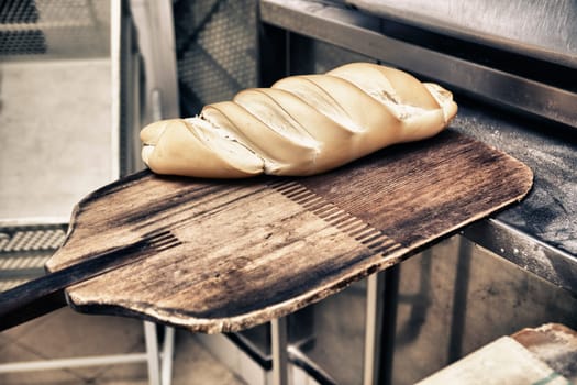 baking peel taking fresh baked bread from oven. Manufacturing process of spanish bread