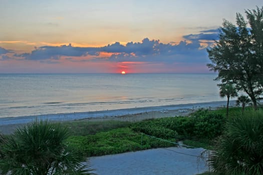 A sunset over the ocean with beach