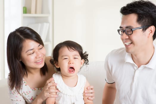 Parents is comforting their crying daughter. Asian family at home.