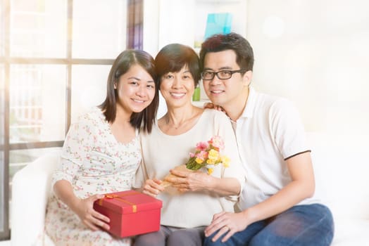 Happy mothers day. Asian senior mom received gift box and flowers from her young children. Family living lifestyle at home.