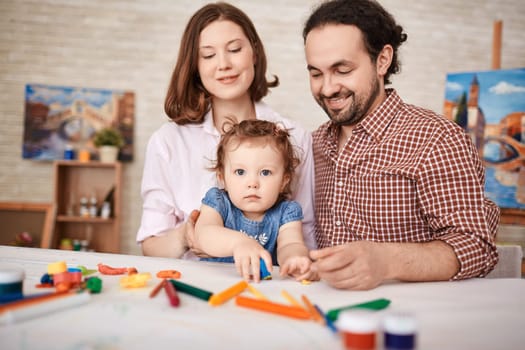 Young parents and pretty daughter playing together