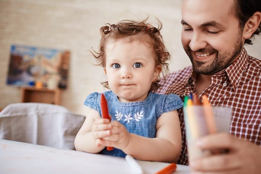 Handsome man and his small daughter with crayon