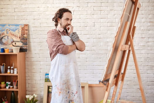 Young artist looking at canvas in studio