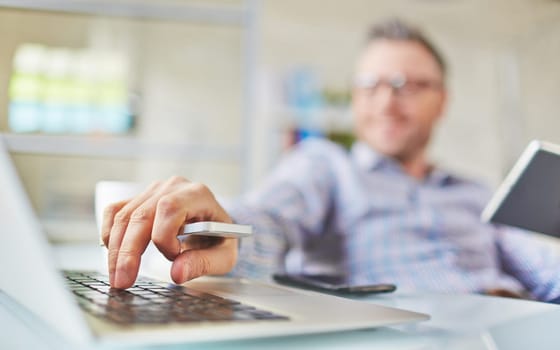 Male hand with cellphone over laptop keypad