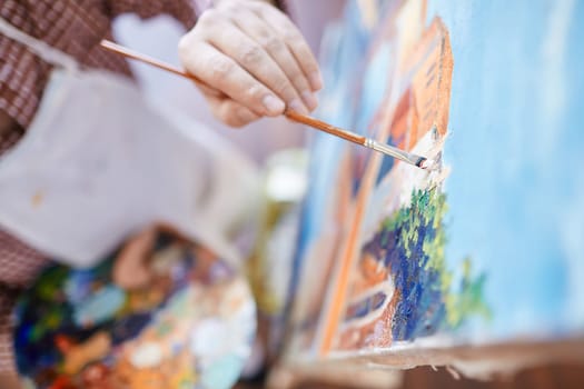 Hand of artist with paintbrush painting on canvas