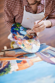 Man with paintbrush mixing water-colors