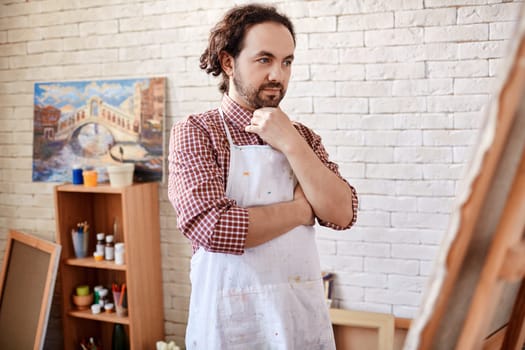Pensive artist looking at canvas in studio