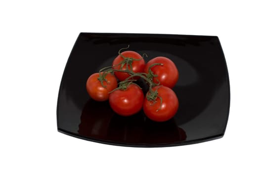 branch of red tomatoes on a black plate