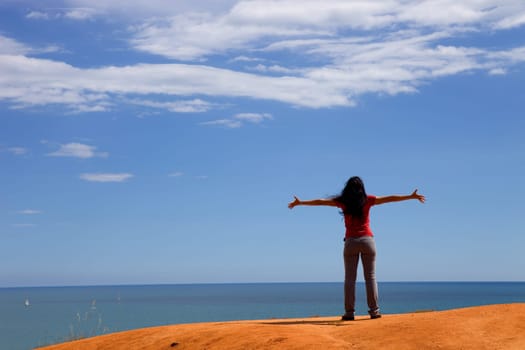 young happy woman at the coast with open arms