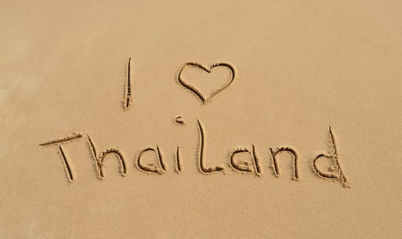 The text 'I love Thailand' written in the sand at a tropical beach..