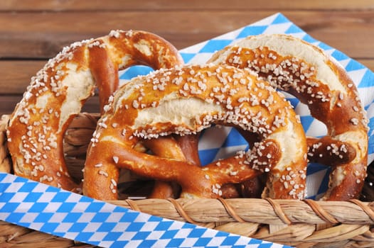 Three original Bavarian lye pretzels with salt in front of a wooden wall