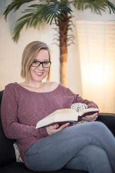 Young woman with glasses reads a book