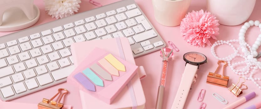 Keyboard and Pink school accessories on light pink, close up. Girly workplace with flowers, Keyboard, pencil, pen and watch. Back to school