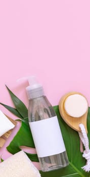 Cosmetic bottle and hair and skin care accessories on palm leaves on pink flat lay, copy space. Brand package mockup. Natural beauty products, Top view