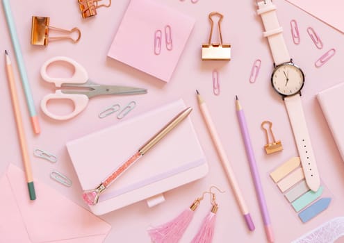 Pink school accessories and stationery on pastel pink background Top view. Girly workplace with notebook, scissors, pencils, pens, sticky note paper, clips and watch. Back to school concept