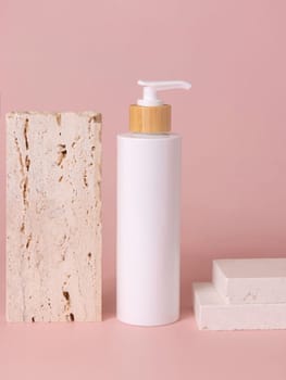 White one pump bottle near beige travertine stone on light pink, close up, mockup. Skincare beauty product. Natural cosmetics, lotion or cleanser. Minimal composition..