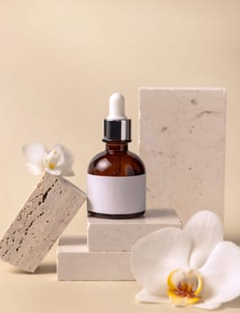Brown glass dropper bottle on stone near white orchid flowers on light yellow, close up, mockup. Skincare handmade beauty product, serum or lotion. Exotic natural cosmetics..