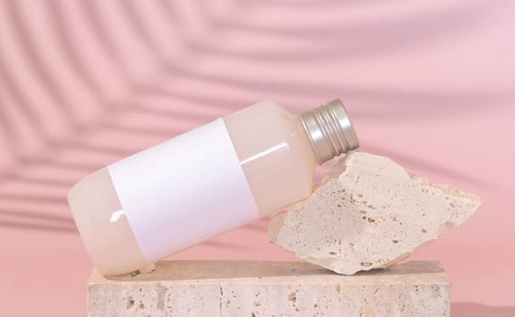 Cosmetic bottle with blank label lies on stone on light pink, palm leaf hard shadow behind, close up, mockup. Skincare beauty product. Natural cosmetics, lotion or cleanser..