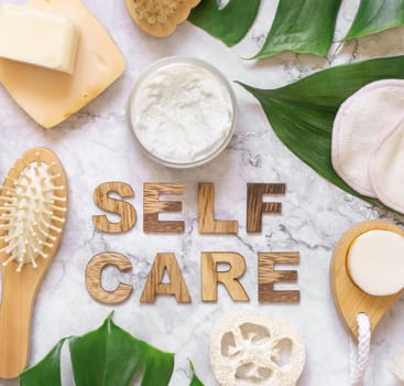 Self Care text near cosmetics, skin and hair care accessories and monstera leaves, copy space. Brand package mockup. Natural beauty products, Top view