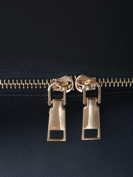 golden zippers with golden zippers are fastened on a black leather object close-up. High quality photo