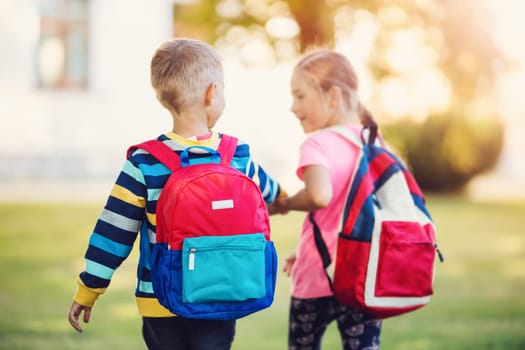 Girl and boy going to the school holding hands to study at it.. Concept of back to school and friendship.