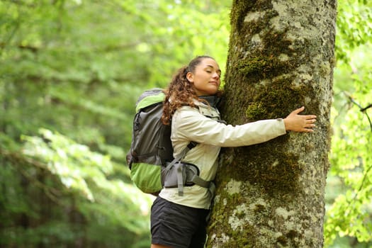 Happy trekker embracing a tree in a forest