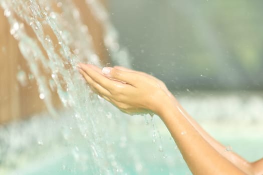Close up portrait of a woman hands cupping catching water under jet in spa