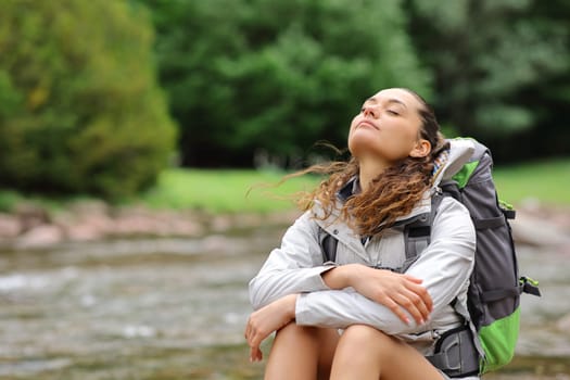 Trekker resting and breathing fresh air in a riverside in the mountain