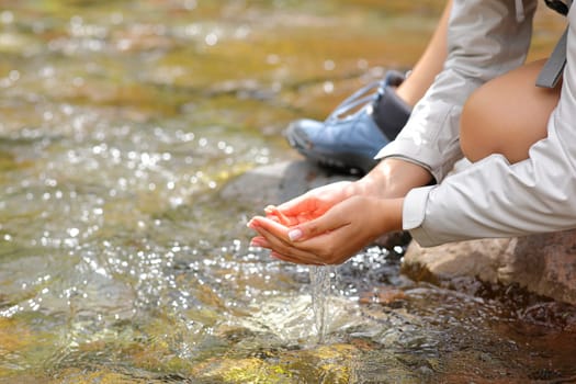 Close up of a woman cupped hands catching water from river