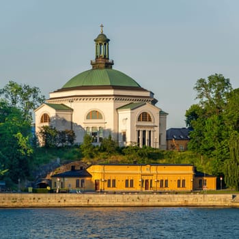 Eric Ericsonhallen concert hall, formerly Skeppsholmen Church until 2009, surrounded by trees. View from Stockholms strom in a sunny summer day, Stockholm, Sweden