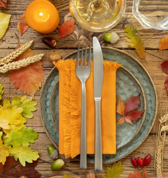 Autumn rustic table setting between leaves and berries on vintage wooden table top view. Thanksgiving, halloween or harvest concept