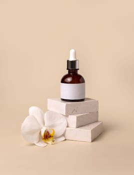 Brown glass dropper bottle on stone near white orchid flowers on light yellow, close up, mockup. Skincare handmade beauty product, serum or lotion. Exotic natural cosmetics..